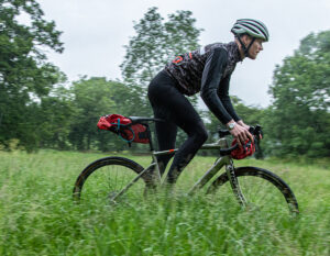 man riding through a feild on a bicycle with saddle bags holding z lok combination lock