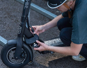 women locking e scooter to metal bike rack with a d lock