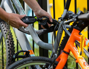 women locking bike with combination chain lock to a playground fence