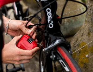 women interting the end of hiplok fx cable lock cable into locking mechanism whilst locking road bike to a stone bridge