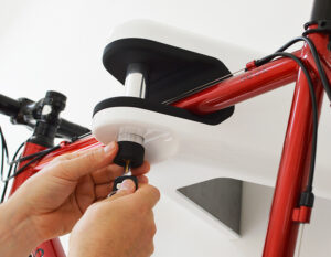 Man unlocking red road bike in AIRLOK wallhanger locking pin with a key on white wall