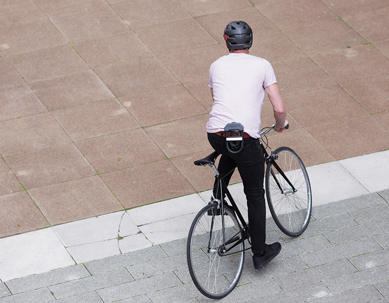 man riding a bike with a D Lock bike lock attached to his belt